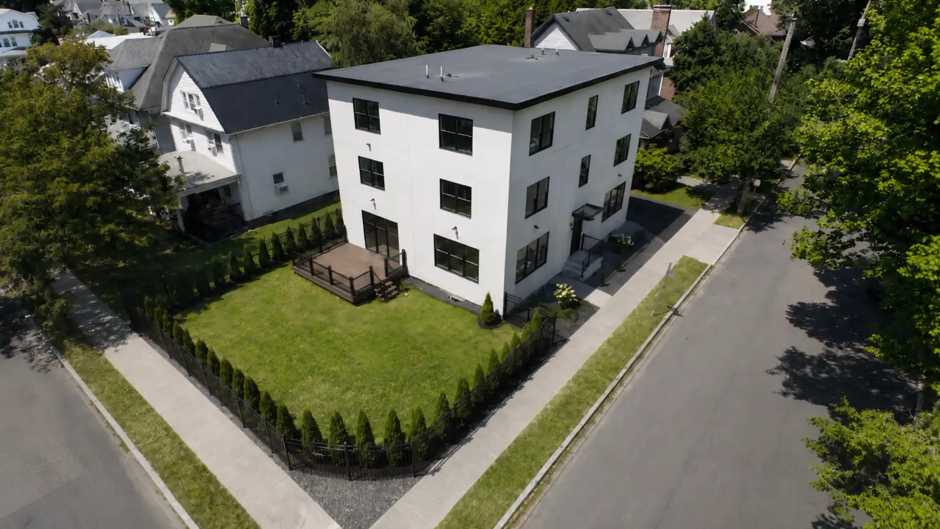 Aerial view of a modern white three-storey residence built by PSI on a landscaped corner lot